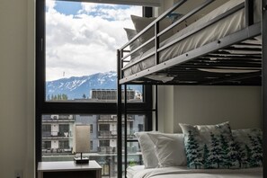 Quarto com beliche e vista para montanhas e edifícios.