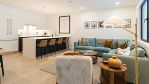 A modern living space with a kitchen, dining area, and a cozy seating area with a sofa and a coffee table. - Max Send in Mackenzie Village (Revelstoke)