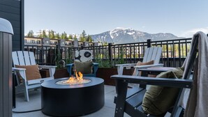 A patio with outdoor seating, a fire pit, and a mountain view. - That 70s Chalet in the Mackenzie Village (Revelstoke)