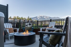 Eine Terrasse mit Sitzgelegenheit im Freien, einem Feuerkorb und Blick auf die Berge.