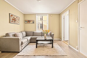 A living room with a sectional sofa, a coffee table, a rug, and two framed artworks on the wall. - City Center Apartment with balcony (Bergen)