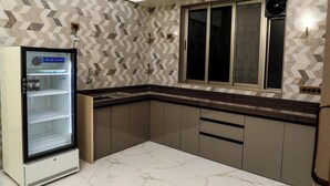 Una cocina moderna con refrigerador integrado, una ventana con persianas y un salpicadero con diseño de espiga.