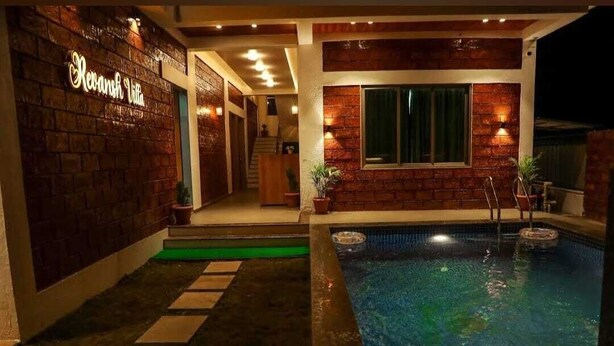 Un área de piscina con un muro de ladrillo y un cartel que dice 'Revansh Villa'.