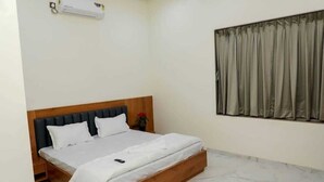 Una cama individual con cabecera de madera, ropa de cama blanca y un control remoto sobre la cama.