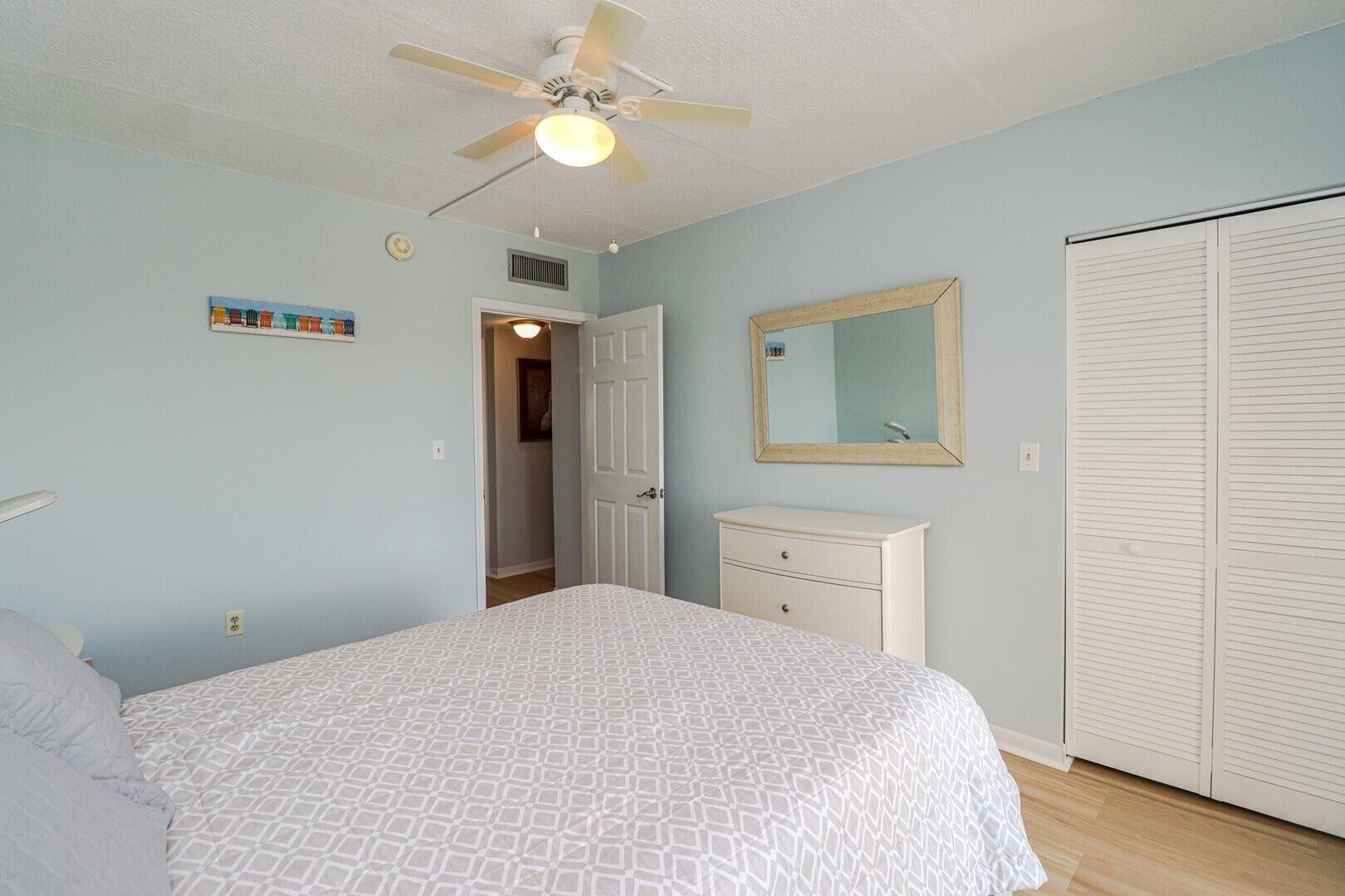 A bedroom with a bed, a dresser, a mirror, and a closet.