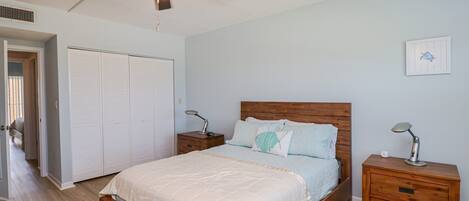 A bedroom with a wooden bed, two bedside tables, a ceiling fan, and a white wardrobe.