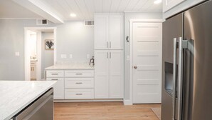 A modern kitchen with white cabinetry, a stainless steel refrigerator, and a marble countertop. - Island South 2-Beautiful Oceanfront Ground Floor, Two Bedroom Condo (St. Augustine)