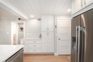 A modern kitchen with white cabinetry, a stainless steel refrigerator, and a marble countertop. - Island South 2-Beautiful Oceanfront Ground Floor, Two Bedroom Condo (St. Augustine)