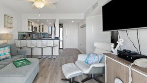 Een moderne woonkamer met een bank, een salontafel, een televisie en een houten dressoir met een telefoon.