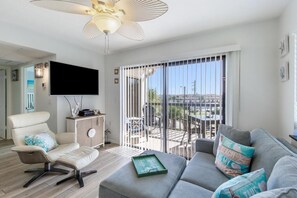A modern living room with a sofa, a chair, a flat-screen TV, and a ceiling fan. - Ocean Village Club Condo D31 (St. Augustine)