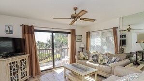 Ein Wohnzimmer mit Fernseher, Sofa und Deckenventilator.