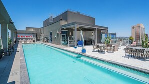 A rooftop pool with a covered seating area, a modern building in the background, and a clear blue sky. - Kenect 2310 (Phoenix)