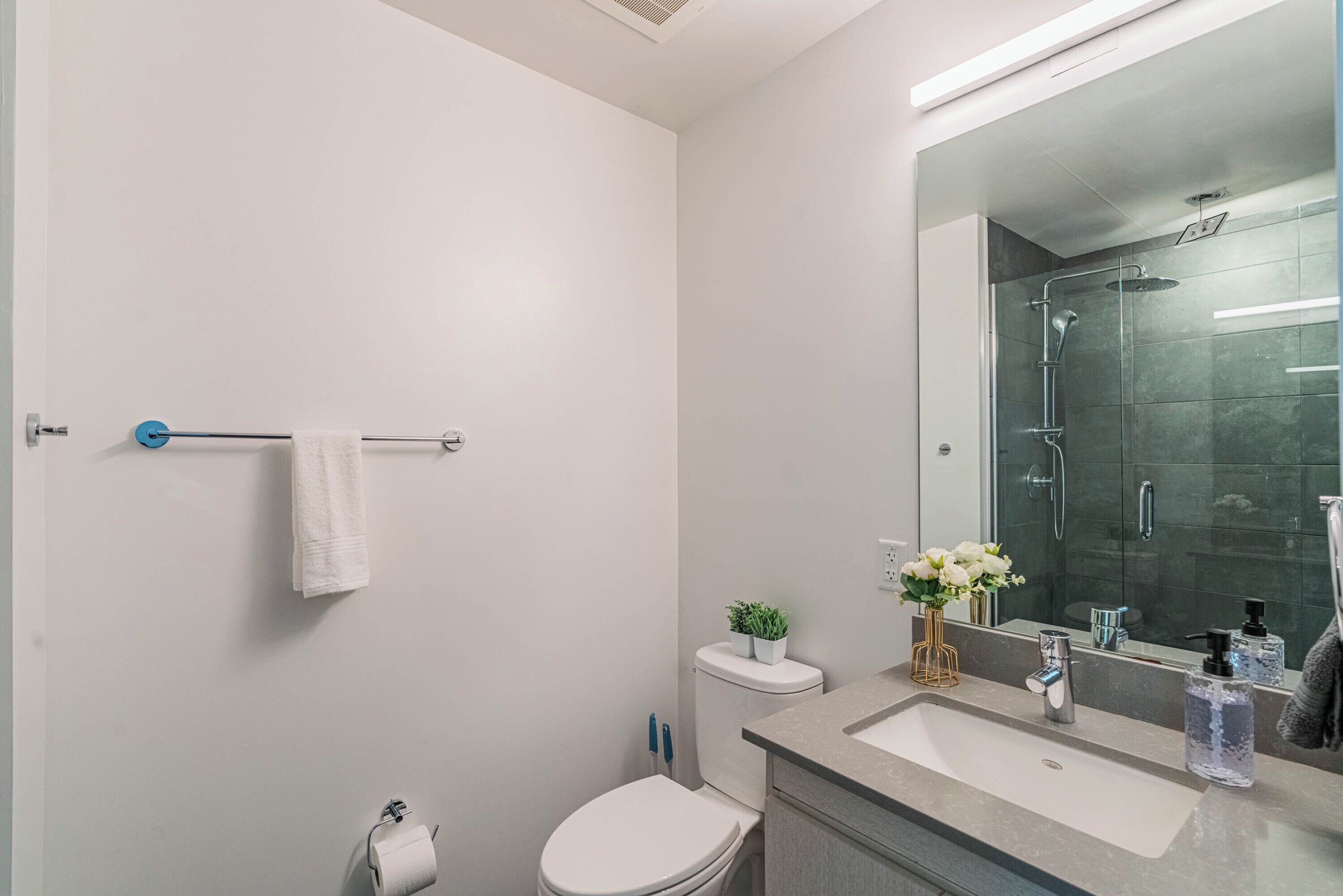 A modern bathroom with a toilet, sink, and shower.