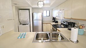 Eine kompakte Küche mit Spülbecken aus Edelstahl, einem Einbauofen und einer Kaffeemaschine.