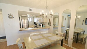 Ein Essbereich mit einem Holztisch und Stühlen, einer Chandelier und einer Küche im Hintergrund.