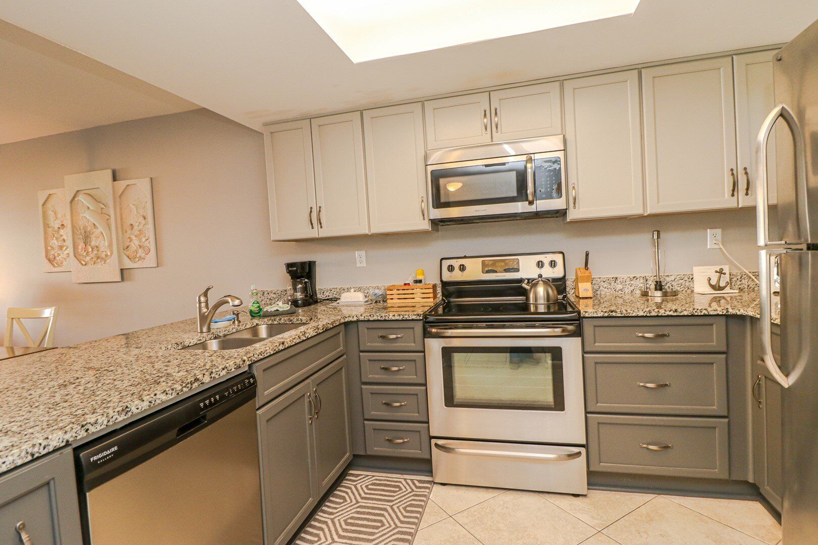 A modern kitchen with granite countertops, stainless steel appliances, and grey cabinetry.