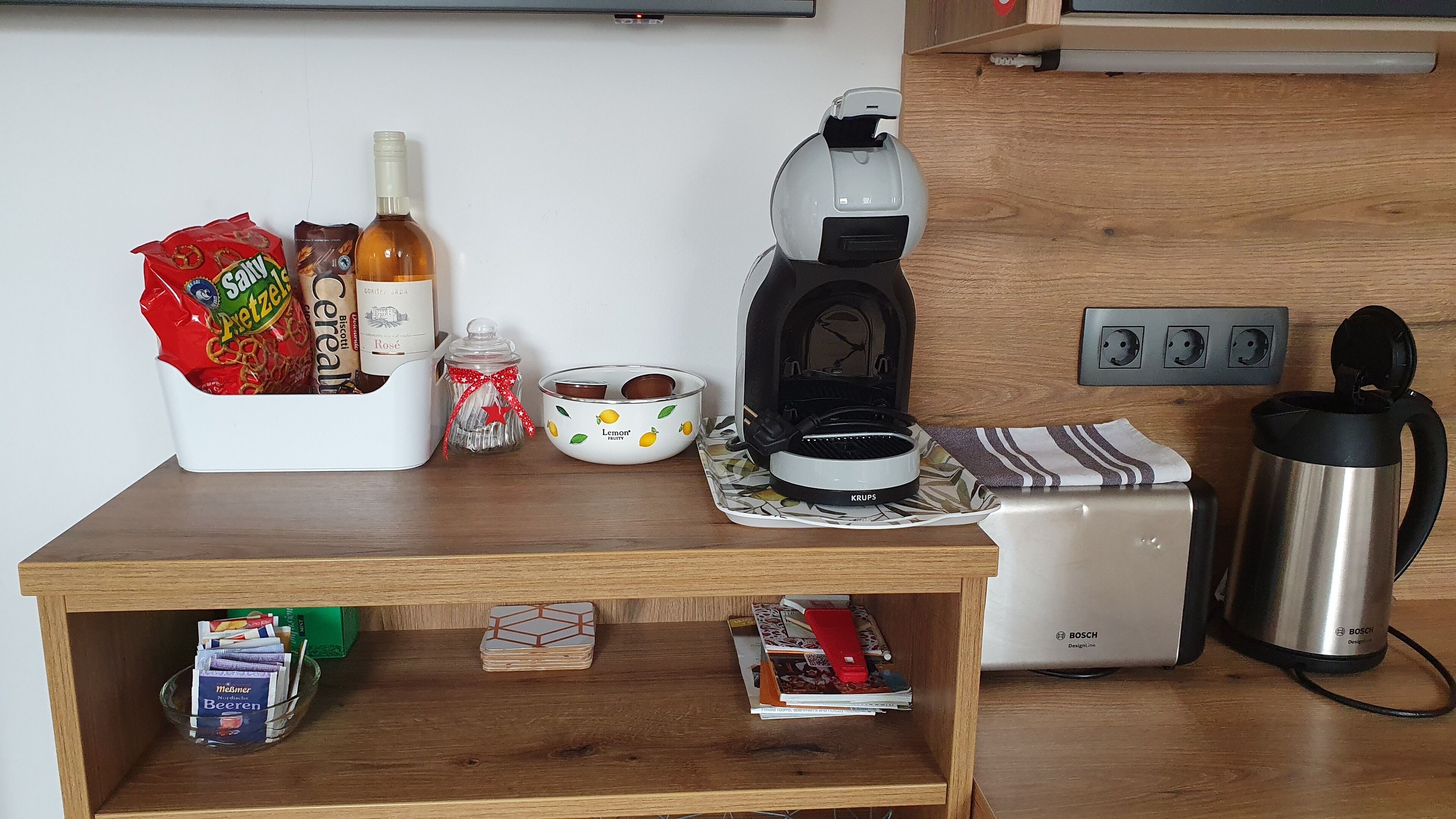 Uma bancada de cozinha com uma cafeteira, uma torradeira, uma chaleira e diversos alimentos.