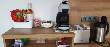 Uma bancada de cozinha com uma cafeteira, uma torradeira, uma chaleira e diversos alimentos.