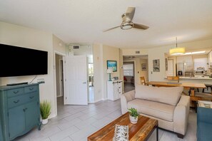 A living room with a sofa, coffee table, TV, and a ceiling fan. - Ocean Village Club Condo Q26 (St. Augustine)