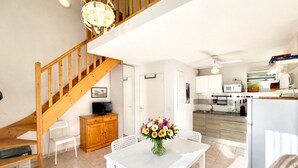 A modern kitchen with white cabinets, a microwave, and a sink. There is a wooden staircase leading to another level. - L’Instant Douceur, 2 guests, Pool in Calvisson (Calvisson)