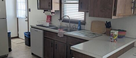 A modern kitchen with wooden cabinets, a built-in sink, and a ceiling fan.