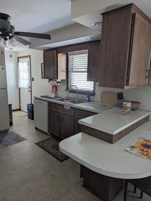 A modern kitchen with wooden cabinets, a built-in sink, and a ceiling fan. - Spacious Frederick County Retreat (Middletown)