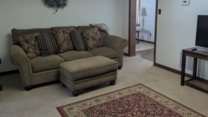 A living room with a sectional sofa, a red and beige patterned rug, a ceiling skylight, and a wreath on the wall. - Spacious Frederick County Retreat (Middletown)