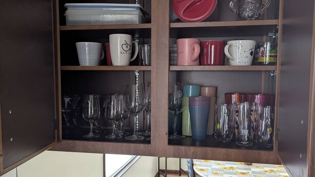 A kitchen with wooden cabinets, a dining table with chairs, and various kitchenware including cups, glasses, and a canister. - Spacious Frederick County Retreat (Middletown)
