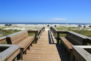 A wooden boardwalk leading to a beach with benches and umbrellas. - St Augustine Beach & Tennis Club 409-Three Bedroom Oceanfront Condo (St. Augustine)