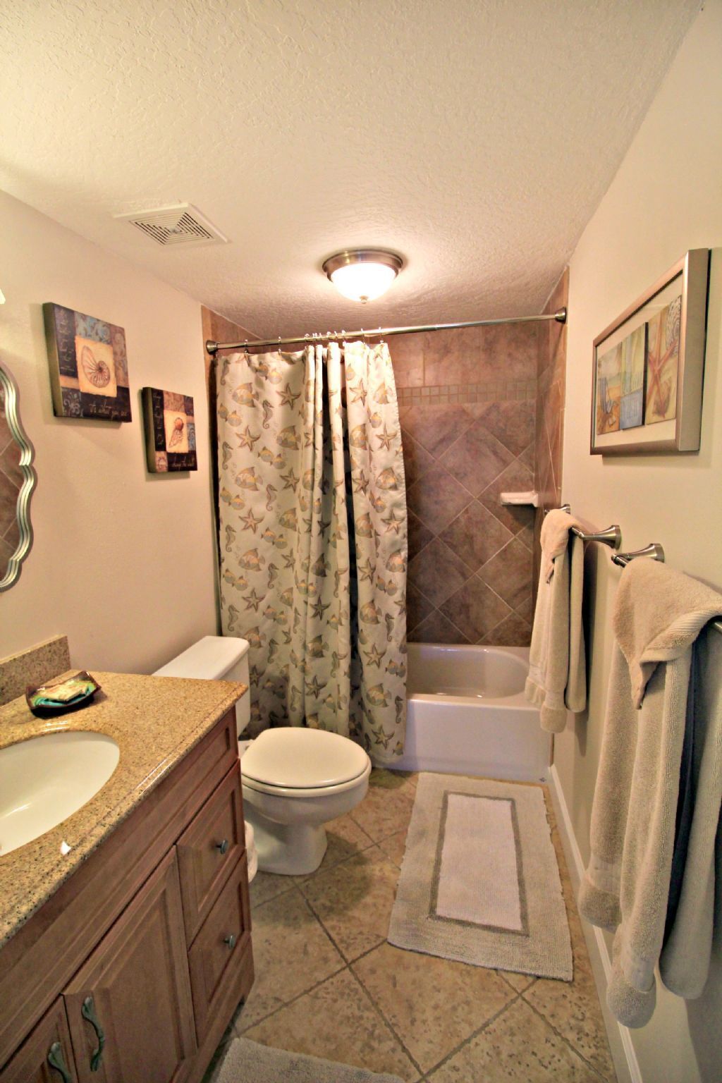 A bathroom with a toilet, sink, bathtub, and shower curtain.