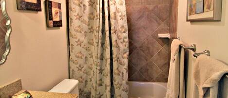 A bathroom with a toilet, sink, bathtub, and shower curtain.