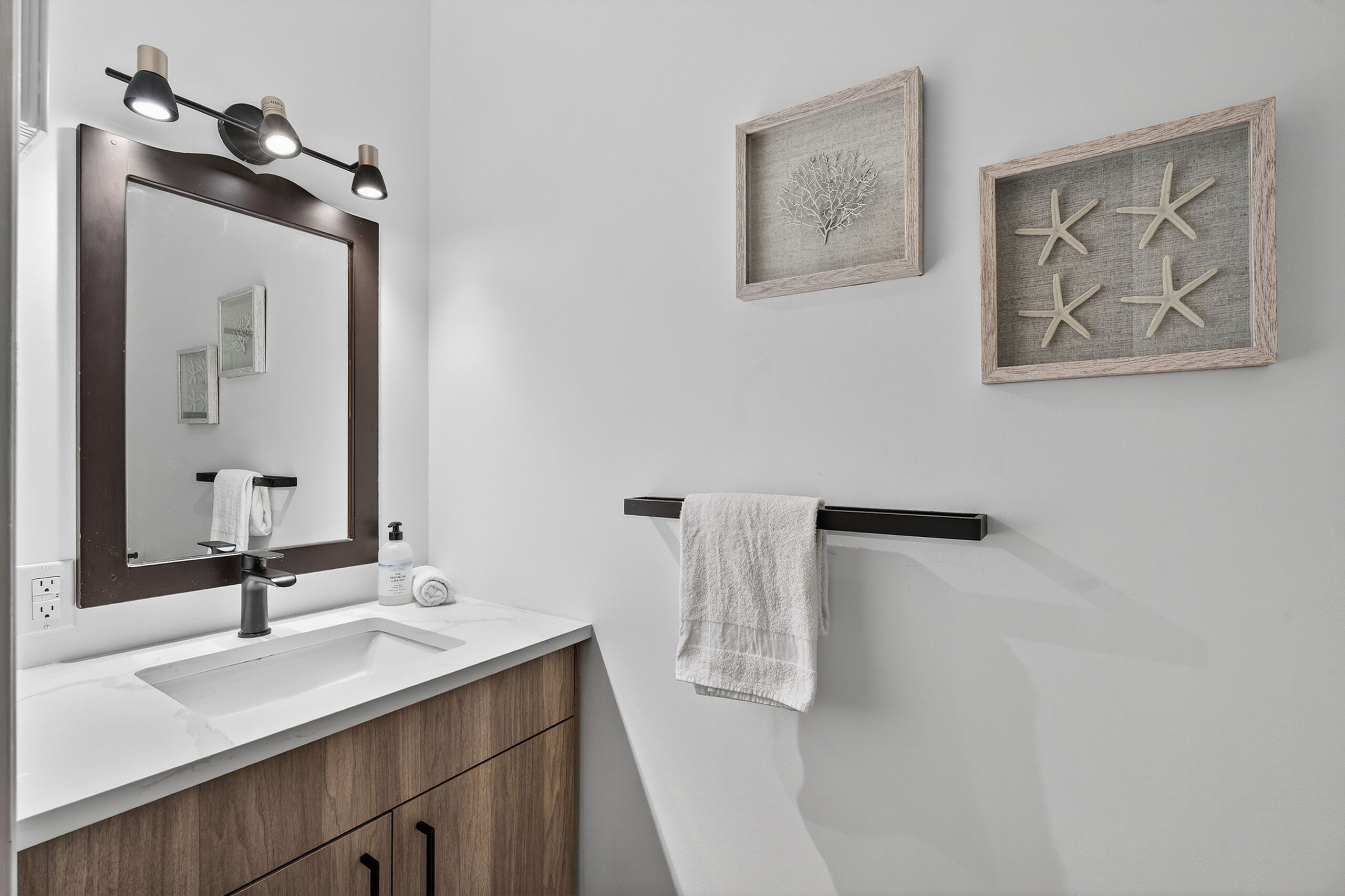 Un baño con un espejo grande, un lavabo y un perchero para toallas.