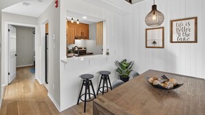 A modern kitchen with wooden cabinets, a built-in island with stools, and a hanging pendant light. - 426 Hotel du Lac (Mont-Tremblant)