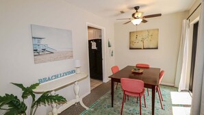 Un comedor con una mesa, sillas, un ventilador de techo y un cuadro en la pared.