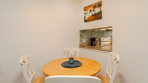 Comedor con una mesa redonda de madera, sillas blancas y un posavasos azul.