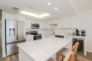 Una cocina moderna con armarios blancos, electrodomésticos de acero inoxidable y una isla central.