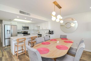 Una cocina moderna con armarios blancos, un refrigerador de acero inoxidable y un microondas.