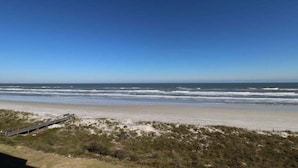Een strand met een houten looppad dat naar het strand leidt, zandduinen en de oceaan.