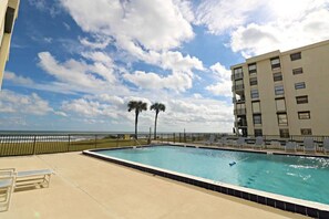 Ein Pool mit Meerblick, ein Gebäude mit Balkonen und ein klarer Himmel.