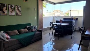 Una sala de estar con un sofá, una mesa de comedor con sillas y una zona de cocina.