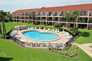 Ein Hotel mit einem großen Pool, umgeben von Liegestühlen und einem gepflegten Rasen.