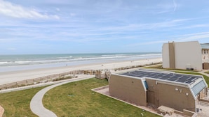 Ein Hotel an der Küste mit Blick auf den Strand, einem gewundenen Weg und einem Gebäude mit Solaranlage.