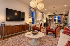 Ein modernes Wohnzimmer mit Flachbildfernseher, rundem Couchtisch und einer Couch.