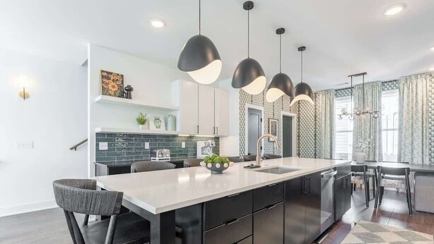 A modern kitchen with a central island, black cabinets, and pendant lighting. - 2 Music City Homes | 20 Beds | Firepit & Hot Tub (Nashville)