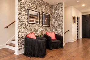 A staircase with a black and white patterned wall, two black chairs with red cushions, and a framed picture of a piano. - 2 Chic Nashville Homes | Rooftops & Skyline Views (Nashville)