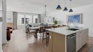 A modern kitchen with a central island, dining area with chairs, and a large window. - 2 Chic Nashville Homes | Rooftops & Skyline Views (Nashville)