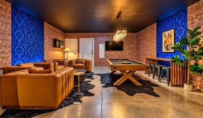 Ein Billardraum mit Billardtisch, Ledersofas und einer Bar.