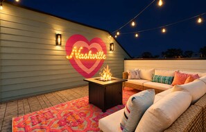 An outdoor seating area with a fire feature, a neon sign, and a patterned rug. - Hot Tub Game Room 20 Beds & Bunk Room 3500sqft (Nashville)