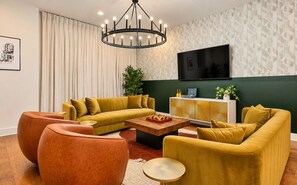 A modern living room with a sectional sofa, a coffee table, and a television mounted on the wall. - Hot Tub Game Room 20 Beds & Bunk Room 3500sqft (Nashville)