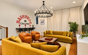 A modern living room with a yellow sofa set, a coffee table, and a chandelier. - Hot Tub Game Room 20 Beds & Bunk Room 3500sqft (Nashville)